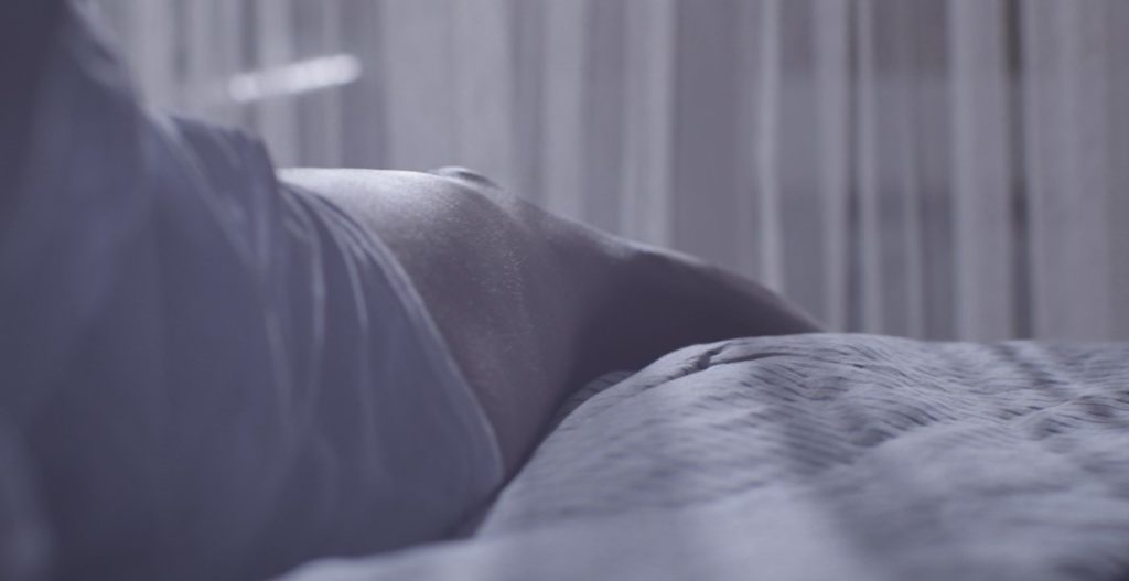 Une jeune femme s'asseoit sur son lit quand elle a pris du CBD quand elle se prépare à se coucher.