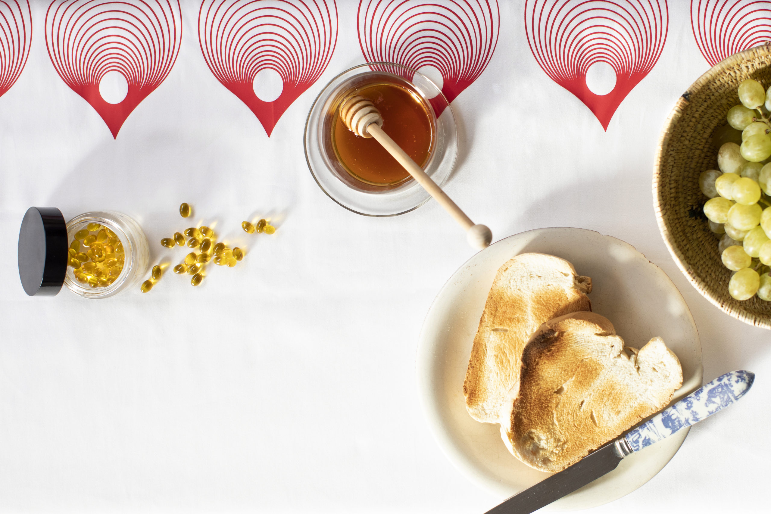 des gélules de CBD sur une table au petit-déjeuner avec une tartine et du miel pour expliquer quand il est possible d'en prendre.