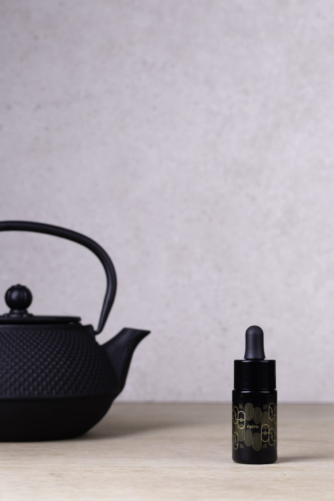 l'huile de cbd égérie à côté d'une théière noire, posée sur une table.
